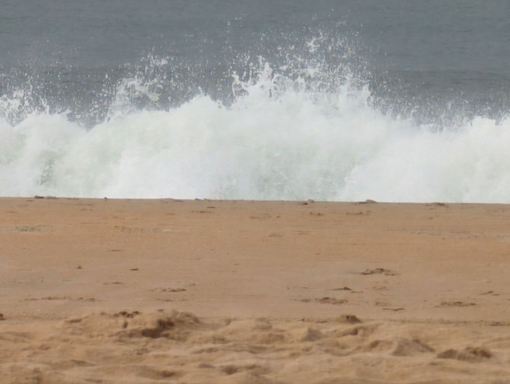 Waves crashing in to a sandy beach 