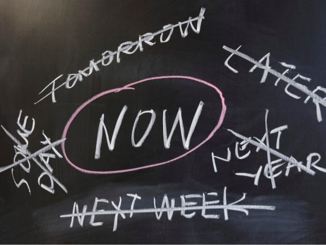 Blackboard with words like 'Tomorrow' 'Later' 'Next Year' all written in chalk, but scored through. The word 'NOW' however, is circled in a red chalk.