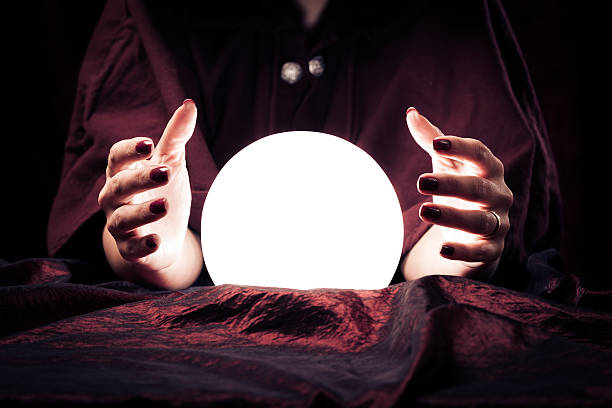 Fortune teller's crystal ball, illuminated, an open palmed hand on either side.
